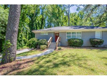 Charming single-story home features a gray brick exterior, green lawn and a red front door at 2755 Rockcliff Se Rd, Atlanta, GA 30316