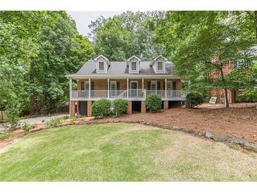 Charming brick home with a well-manicured lawn, mature trees, and a welcoming front porch at 4314 Arbor Bridge Ct, Marietta, GA 30066