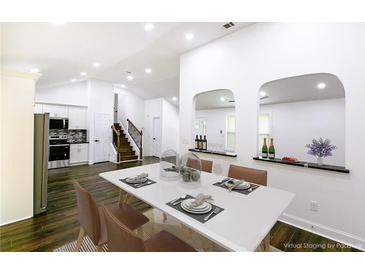 Bright dining area featuring stylish table setting, dark hardwood floors, and open layout to the kitchen at 1241 Bethsaida Rd, Riverdale, GA 30296