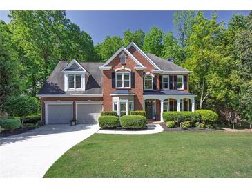 Beautiful brick home featuring lush landscaping, a two-car garage, and a well-manicured lawn at 7014 E Hills Way, Woodstock, GA 30189