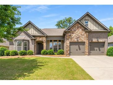 Charming home featuring a stone and brick facade, complemented by a well-manicured lawn and attached two car garage at 6995 Tybridge St, Cumming, GA 30040