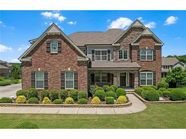Stately brick home boasts manicured landscaping, a stone accent wall, and a welcoming front porch at 2520 Wood Fern Ln, Cumming, GA 30041