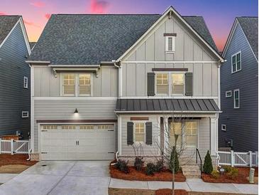 Charming two-story home with gray siding, well-manicured landscaping and a two car garage at 1006 Fendley St, Woodstock, GA 30188