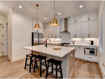 Bright kitchen features white cabinets, stainless steel appliances, pendant lighting, and a large center island with seating at 1006 Fendley St, Woodstock, GA 30188