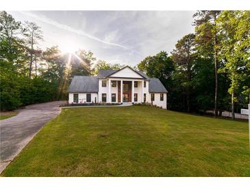 Stunning two-story home with a manicured lawn and elegant, column-lined entryway, surrounded by lush trees at 4 Bentley Trace Mnr, Atlanta, GA 30327