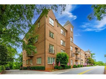 Elegant brick condo building featuring manicured landscaping, and patriotic American flags displayed on the front lawn at 351 Ne Washington Ne Ave # 307, Marietta, GA 30060