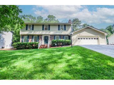 Charming two-story home with manicured lawn, attached garage, and classic architectural details at 1206 Tred Avon Sw Way, Lilburn, GA 30047