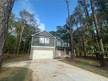 Two-story home featuring a two-car garage, gray siding, brick base and a concrete driveway at 142 Tye St, Stockbridge, GA 30281