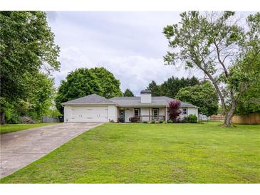 Charming single-story home featuring a well-manicured lawn and an attached two-car garage at 7925 Silversmith Dr, Cumming, GA 30028