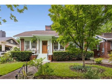 Charming brick home with a cozy front porch, lush landscaping, and a well-manicured lawn at 239 Kings Hwy, Decatur, GA 30030
