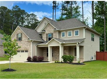 Two-story home with a combination of brick and siding, a well-manicured lawn, and a covered front porch at 4093 Groveland Park Dr, Powder Springs, GA 30127