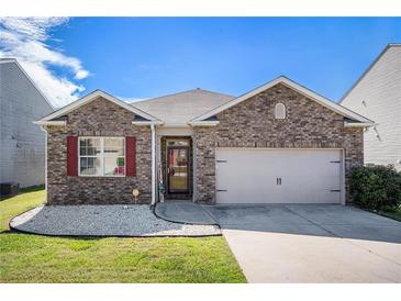 Charming single-story home with brick facade, attached garage, manicured lawn and vibrant red window shutters at 1907 Sea Oats Dr, Hampton, GA 30228