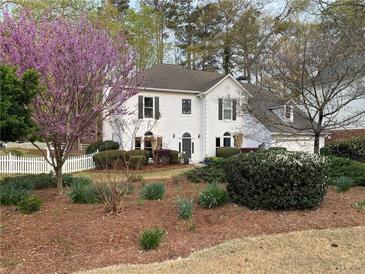 Charming two-story home with white picket fence and mature landscaping, including a beautiful flowering tree at 5440 Cameron Forest Pkwy, Johns Creek, GA 30022