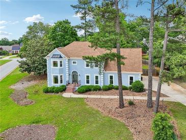 Charming light blue two-story home with well-manicured lawn and mature trees in a desirable neighborhood at 771 James Cir, Lawrenceville, GA 30046