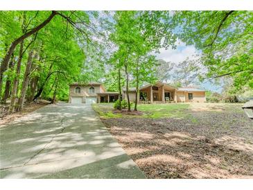 Charming home with a long driveway, attached garage, and inviting front porch surrounded by lush trees at 2228 Walker Dr, Lawrenceville, GA 30043