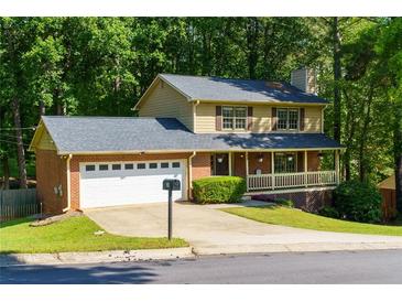 Charming two-story home boasts a brick front, attached garage, a welcoming porch, and a tree-lined yard at 28 Indian Branch Way, Lawrenceville, GA 30043