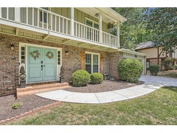 Charming brick home with a welcoming front entrance, light blue double doors, and a second-story balcony at 1080 Northshore Dr, Roswell, GA 30076