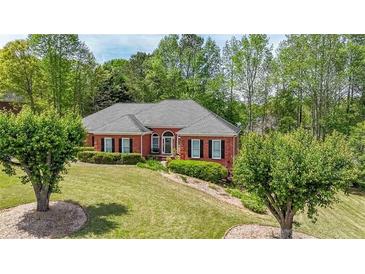 Charming single-story brick home featuring a manicured lawn, mature trees, and a welcoming front entrance at 1420 Arblay Pl, Loganville, GA 30052
