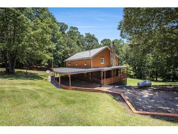 Charming home boasts a metal roof and covered veranda, nestled in a lush landscape at 1795 Hutcheson Ferry Rd, Whitesburg, GA 30185