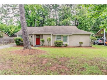 Charming single story home with brick accents, manicured landscaping and a bright red front door at 2469 Newgate Dr, Decatur, GA 30035