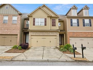 Charming townhome featuring a two-car garage, stone accents and manicured landscaping at 2647 Sardis Chase Ct, Buford, GA 30519