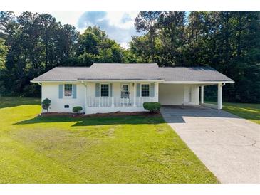 Charming one-story home with white exterior, a carport, manicured lawn, and lovely landscaping at 10 Casey Ln, Cartersville, GA 30121