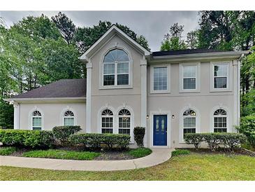 Charming two-story home boasts a well-maintained lawn and landscaped yard with a welcoming blue front door at 2312 Mahogany Glen Pl, Lawrenceville, GA 30043