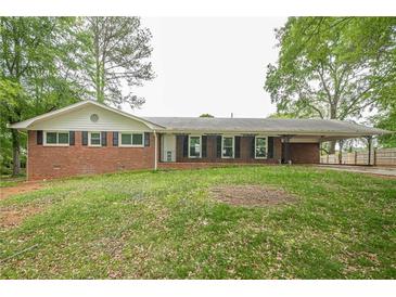 Ranch-style home with a brick exterior, a lawn, and a covered carport on a tree-lined lot at 4935 Golden Sw Cir, Mableton, GA 30126