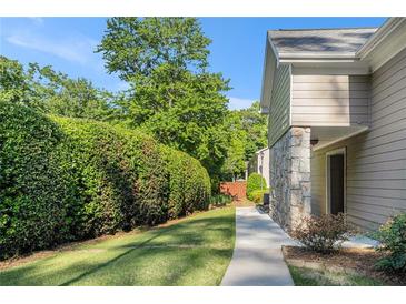 Inviting home exterior with stone accents, sidewalk, grassy area and lush landscaping at 502 Brighton Pt, Atlanta, GA 30328