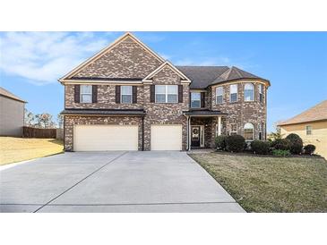 Charming two-story brick home features a two-car garage and manicured lawn on a sunny day at 3621 Guinevere Trce, Douglasville, GA 30135