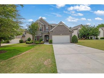 Charming brick home with a well-manicured lawn, two car garage, and a beautifully landscaped front yard at 4050 Pleasant Woods Dr, Cumming, GA 30028