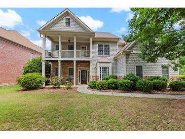Charming two-story home with a welcoming front porch, stone accents, and lush landscaping at 944 Hidden Falls Se Ln, Smyrna, GA 30082