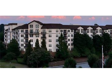 Modern apartment building with dark trim and multiple balconies surrounded by lush greenery and colorful sky at 901 Abernathy Ne Rd # 2050, Sandy Springs, GA 30328