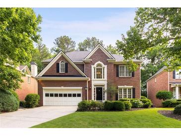 Charming brick home featuring a manicured lawn and attached garage in a lush, green neighborhood at 4679 Glenshire Pl, Atlanta, GA 30338