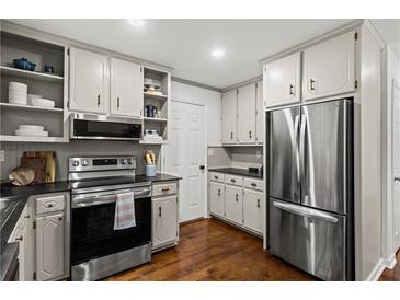 Well-lit kitchen with stainless steel appliances, hardwood floors, and plentiful cabinet storage at 1320 Country Acres Ln, Lawrenceville, GA 30045