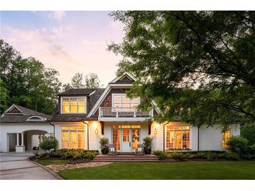 Charming two-story home with a brick walkway, white facade, and balcony against a colorful sunset at 5360 Lake Forrest Dr, Atlanta, GA 30342