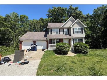 Two-story home featuring a two-car garage, front porch, and manicured front yard landscaping at 4649 Camelot Dr, Douglasville, GA 30135
