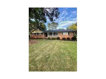 Charming single-story brick home with a well-manicured lawn and mature trees at 1838 Cates Ct, Snellville, GA 30078