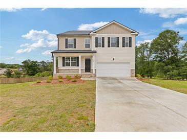 Charming two-story home featuring neutral siding, black shutters, a two-car garage, and a well manicured lawn at 294 Ralph Still Rd, Dacula, GA 30019