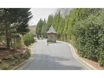 Neighborhood entrance with stone gatehouse and lush landscaping at 9675 Almaviva Dr, Alpharetta, GA 30022
