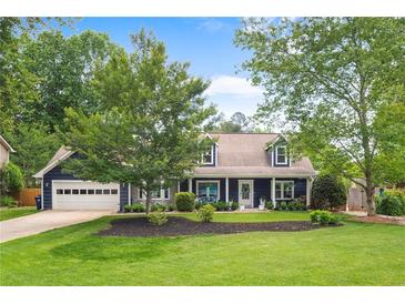 Charming home featuring a well-maintained lawn, lush trees, and a welcoming exterior with a two-car garage at 209 Hearthstone Reach, Peachtree City, GA 30269