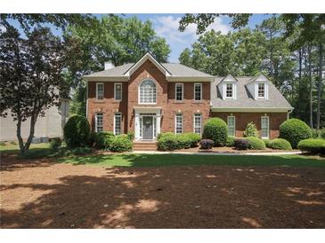 Charming two-story brick home with a well-manicured lawn and mature trees at 1915 Milfield Cir, Snellville, GA 30078