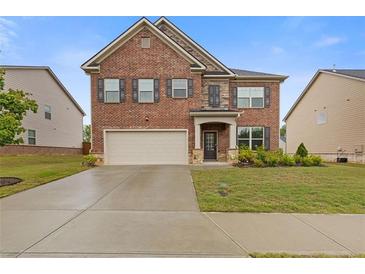 Charming two-story brick home featuring a two-car garage, manicured lawn, and a welcoming entrance at 3825 Sycamore Hill Dr, Loganville, GA 30052
