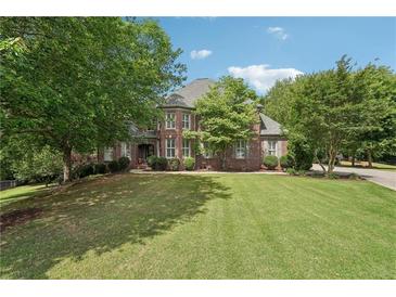 Beautiful brick home with lush green lawn and mature trees, perfect for serene suburban living at 3235 Munsey Ct, Cumming, GA 30041