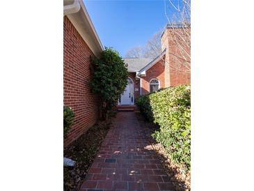 Charming brick home featuring a classic arched entryway and a well-maintained landscaped walkway at 341 Little John Nw Dr, Lilburn, GA 30047