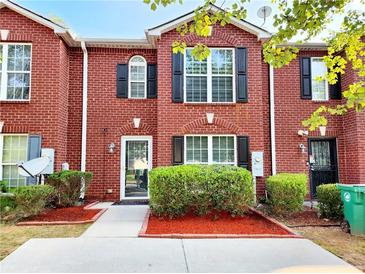 Charming brick townhome with black shutters, well-manicured bushes, and mulch at 2430 Piering Dr, Lithonia, GA 30038