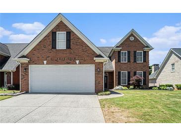 Charming brick home showcasing a well-maintained lawn, two car garage, and classic architectural details at 725 Windsor Place Sw Cir, Grayson, GA 30017