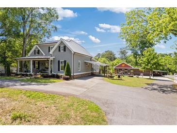 Charming gray home features a metal roof, covered front porch and a long driveway at 527 Main St, Suwanee, GA 30024