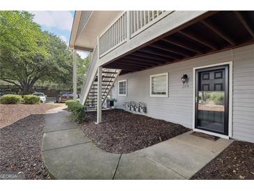 Apartment exterior with gray siding, black door, wood staircase, and trimmed mulch area at 105 Olde Mill Ln, Norcross, GA 30093