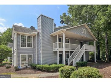 Attractive two-story condo with gray siding, white trim, and lush landscaping creates a welcoming curb appeal at 105 Olde Mill Ln, Norcross, GA 30093